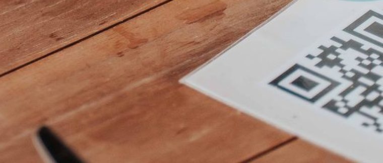 Een geprinte QR sticker die plat op een houten cafétafel is geplakt